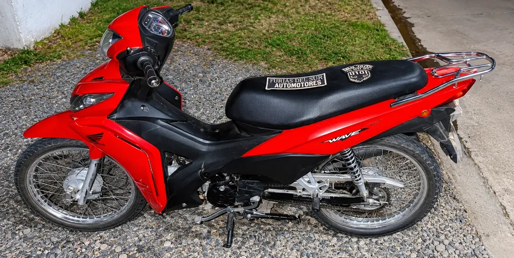Moto roja estacionada en grava